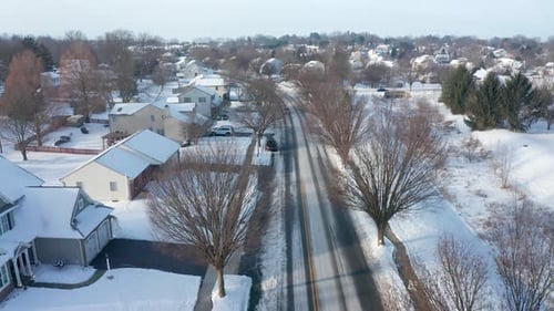 Aerial establishing shot of homes in small town neighborhood development in USA. Snow covered roads