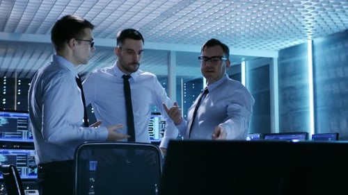 Drei technische Moderatoren diskutieren aktiv im Monitoringraum. Der Systemkontrollraum ist voll