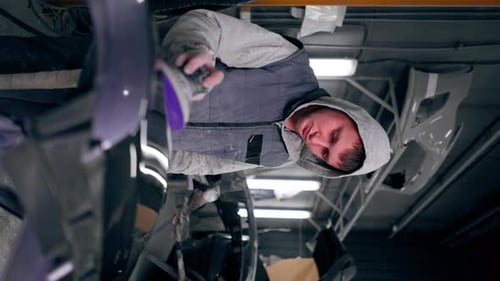 Vertikales Video Automechaniker Nahaufnahme an einer Tankstelle beim Schleifen eines Teils eines grauen Autos, das auf einem liegt