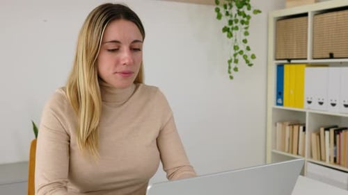 Jovem alegre sorrindo para a câmera enquanto trabalhava no laptop no escritório doméstico