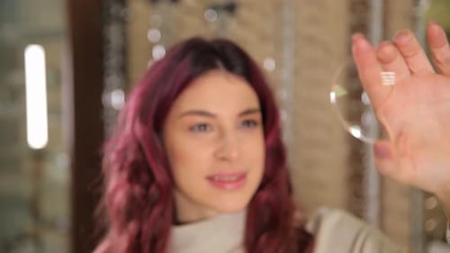 Woman Examines Eyeglass Lens
