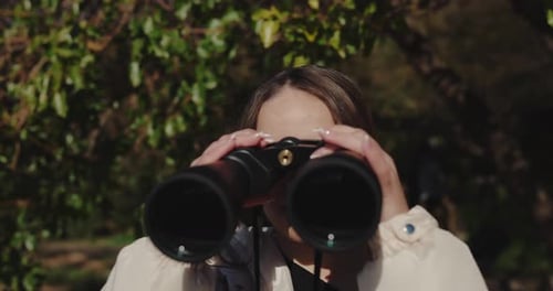 Young Woman Using Binoculars in Nature