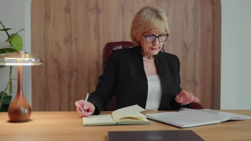 Mujer madura estudia documentos y toma notas en el escritorio