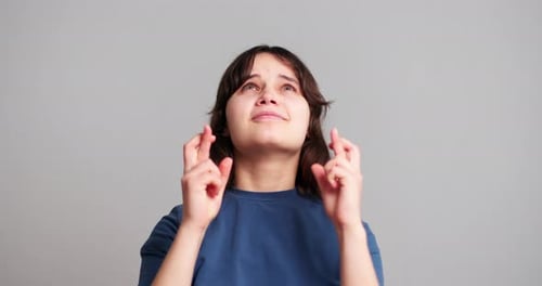 Teen Crossing Fingers and Looking Upward Hopeful