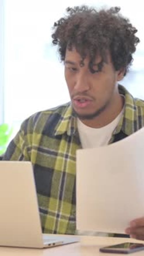 Excited Young Man Working at Desk with Laptop