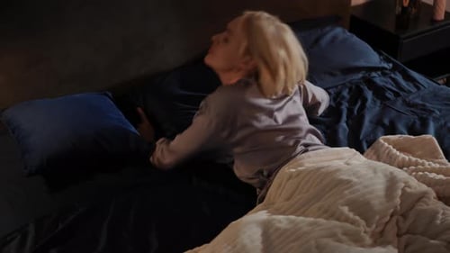 Blonde Woman Unable to Sleep, Covers Head with Pillow