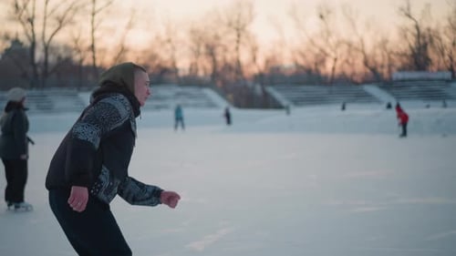 Side View Young Boy Gliding on Ice Rink at Sunset
