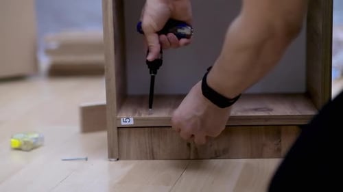 Man Assembling Wood Shelf with Screwdriver