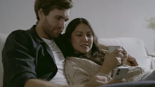 Couple Relaxing on Sofa Looking at Phone Together