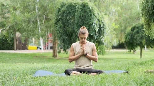 Man Meditating and Stretching While Doing Yoga Outdoors in a Park