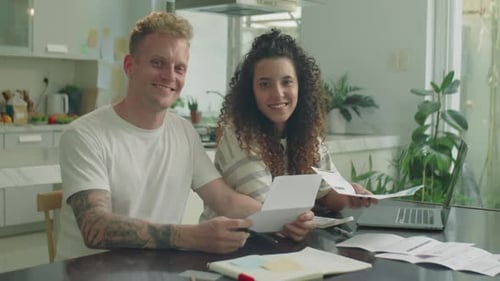 Smiling Couple Reviews Finances at Home Together