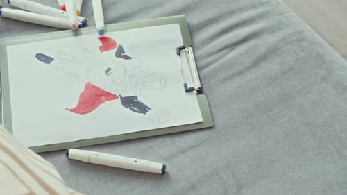 Superhero Drawing on Clipboard with Markers on Couch