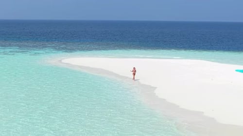 Aerial View of a Remote Island in the Maldives Featuring a Woman Walking on a White Sand Beach