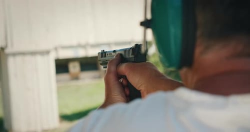 Hombre apuntando y disparando una pistola semiautomática durante la práctica del campo de tiro
