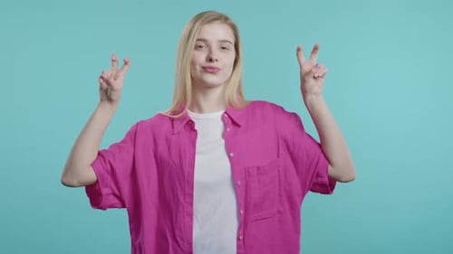 Woman Makes Peace Sign in Front of Blue Background
