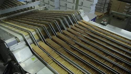 lot of square cookies are pressed together on conveyor line before being packed