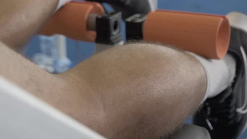 Pessoa deitada em uma máquina de fitness apoiando os músculos das panturrilhas.
