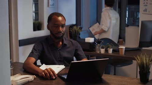 Männlicher Manager analysiert Diagramme auf Dokumenten und Laptop