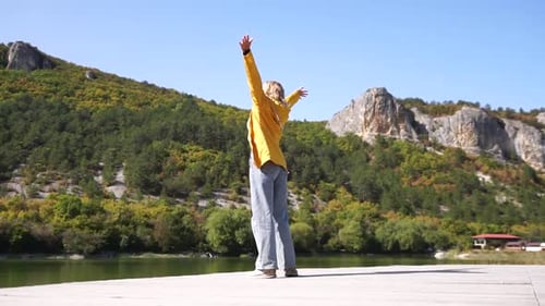 Woman Enjoying Nature on Dock With Arms Raised