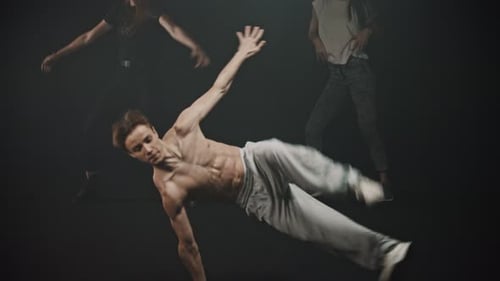 A Shirtless Man Performing Breakdancing Tricks Two Women Dancing on