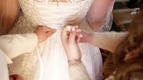 Helpers Adjusting Bride's Lace Gown Back