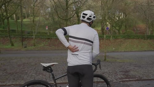Cyclist placing phone in jersey pocket beside road