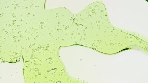 Transparent Green Cosmetic Gel Fluid With Molecule Bubbles and Oil on White Background