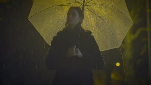 Sentimentale einsame junge Frau weint ängstlich in regnerischer Nacht