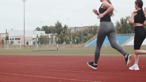 Running Sports Competitions at the Stadium Four People Men and Women Run Competing Rear View Women