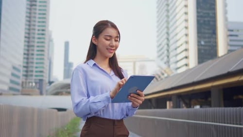 Asian young businesswoman using digital tablet while standing in the city.