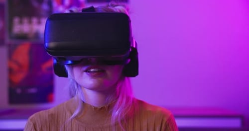 Woman Using Virtual Reality Headset in Neon Lit Room