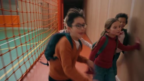 Happy School Children Running Down Hallway Together