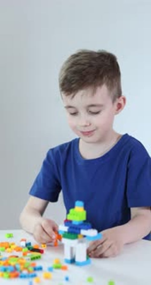 Juguete de construcción. Niño jugando con bloques de construcción en la mesa contra un fondo claro