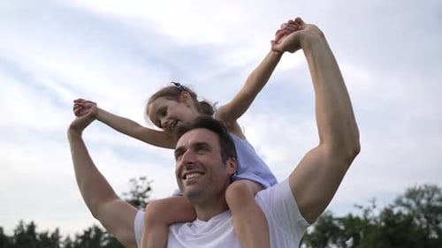 Happy Father Carries Daughter on Shoulders