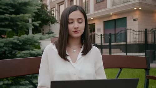 Young Woman Using Laptop on Park Bench
