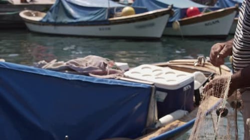 Hände eines alten Fischers, der seine Netze für einen neuen Fang vorbereitet