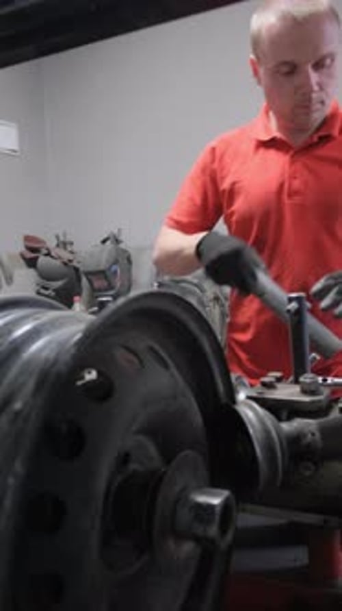 Man in Orange Shirt Gestures While Working on Machine Vertical Video