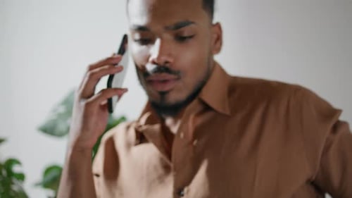 Young adult man talking on his cellphone indoors