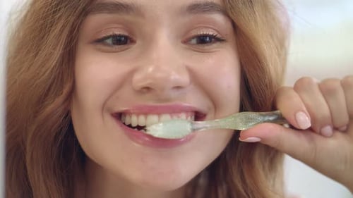 Smiling Woman Brushing Teeth in the Morning
