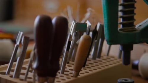 Close-up of Crafting Tools and Metal Press on Table in Leather Workshop