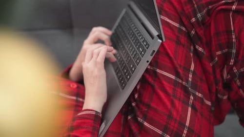 Woman in Red on Sofa at Home with Laptop Christmas Tree and Gifts