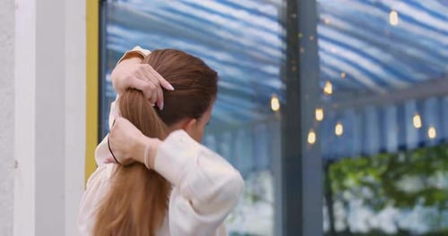 Woman Puts Her Hair Up in Ponytail