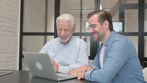 Adult and Senior Discussing Technology at Desk