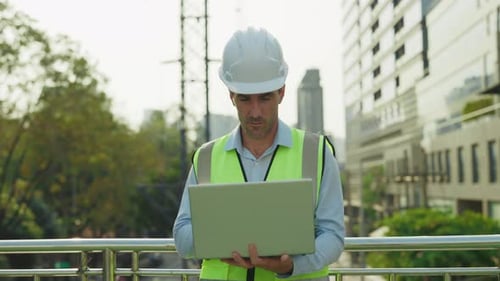Portrait of Man Engineer Looking at Camera Holding Laptop Standing Against Factory Building