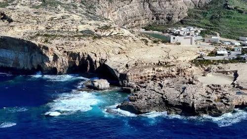 Breathtaking aerial drone view of rugged limestone cliffs and hidden sea caves at Dwejra Bay Gozo