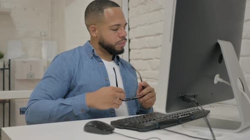 Man Working at Computer Rubs His Eyes