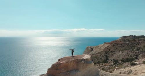 Aerial View of a Man on the Top of a Rock on the Birch of the Sea