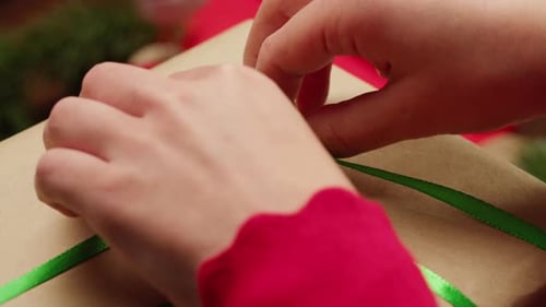 Hands Untie Green Ribbon on Christmas Gift