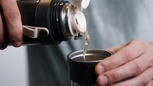 Man Pours Hot Tea From Thermos Into Cup