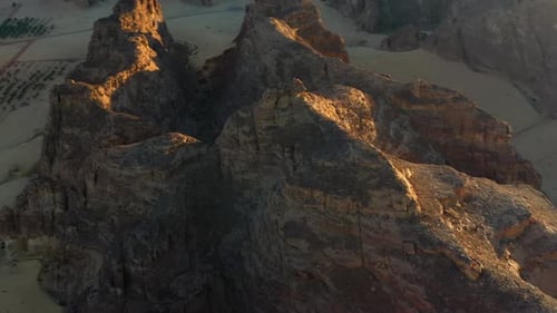 Aerial view around sandstone mountains during dramatic evening light in Al Ula, Saudi Arabia -